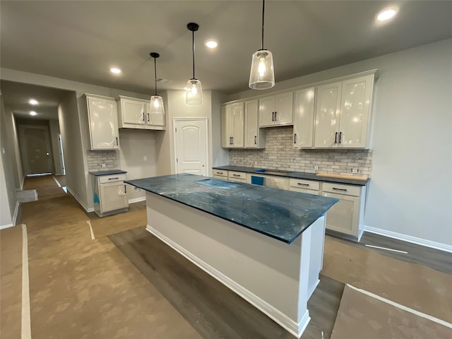 kitchen with a center island, decorative backsplash, hanging light fixtures, dark wood-type flooring, and white cabinets