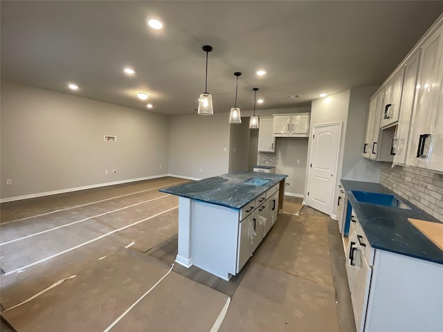 kitchen with a center island, white cabinetry, dark stone countertops, backsplash, and hanging light fixtures