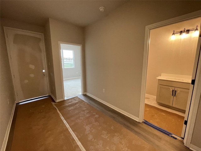 unfurnished bedroom with ensuite bathroom and wood-type flooring