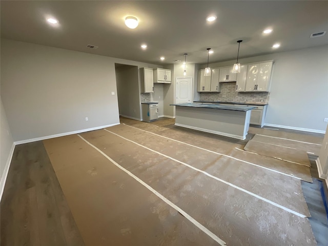 kitchen featuring decorative light fixtures, decorative backsplash, white cabinets, and a center island