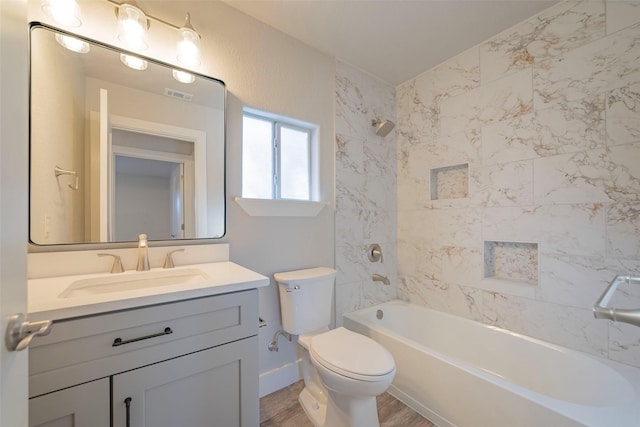 full bathroom with vanity, hardwood / wood-style floors, tiled shower / bath combo, and toilet