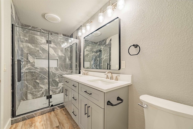 bathroom with a textured ceiling, toilet, an enclosed shower, vanity, and hardwood / wood-style flooring