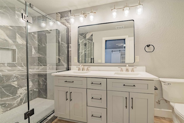 bathroom with vanity, toilet, and a shower with door