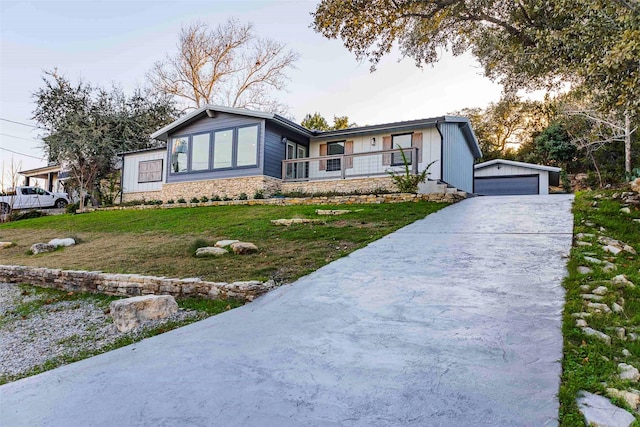 view of front of house with a porch, a garage, an outbuilding, and a front lawn