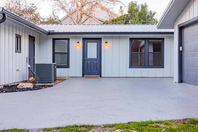 view of exterior entry featuring a garage and central AC unit