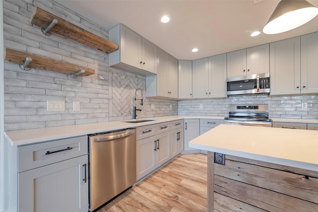 kitchen featuring stainless steel appliances, light hardwood / wood-style flooring, tasteful backsplash, and sink