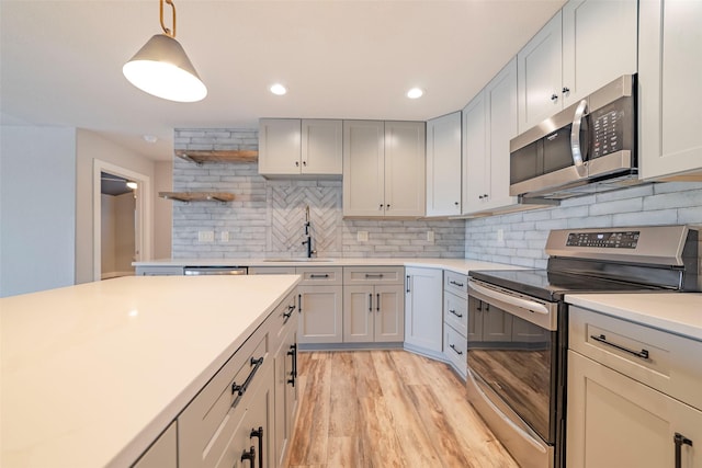 kitchen with sink, tasteful backsplash, decorative light fixtures, light hardwood / wood-style floors, and stainless steel appliances