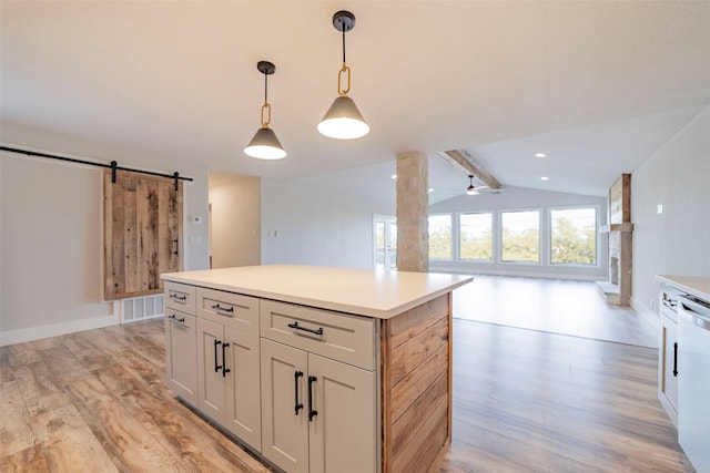 kitchen with light wood-type flooring, pendant lighting, lofted ceiling with beams, a barn door, and a center island