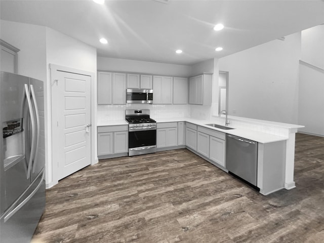 kitchen with appliances with stainless steel finishes, backsplash, gray cabinetry, sink, and dark hardwood / wood-style floors