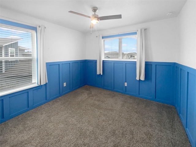 spare room featuring ceiling fan and dark carpet