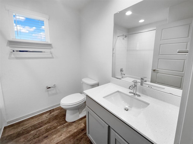 full bathroom featuring hardwood / wood-style floors, vanity, toilet, and tiled shower / bath combo