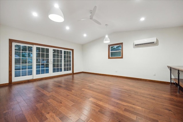 empty room featuring hardwood / wood-style flooring, vaulted ceiling, an AC wall unit, and ceiling fan