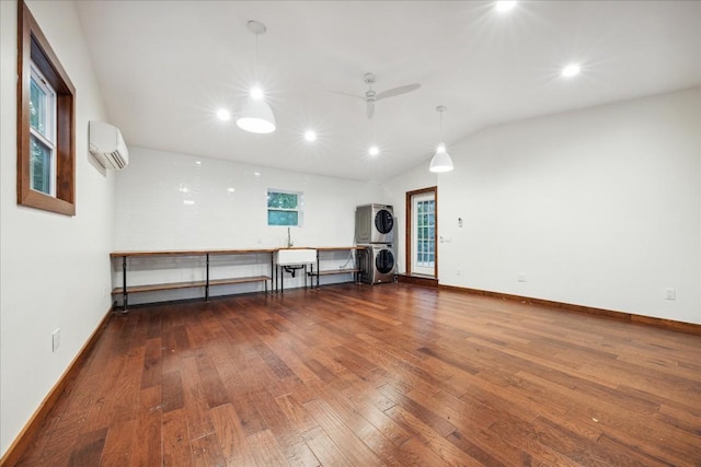 interior space with lofted ceiling, stacked washer and clothes dryer, ceiling fan, dark wood-type flooring, and a wall unit AC