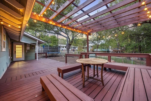 wooden deck featuring a trampoline and a pergola