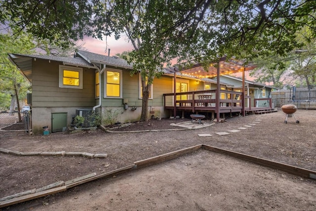 back house at dusk featuring a deck and a pergola