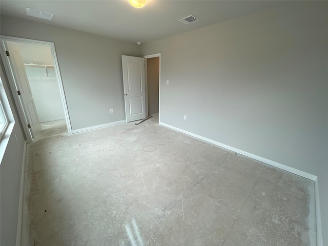 unfurnished bedroom featuring a walk in closet and a closet