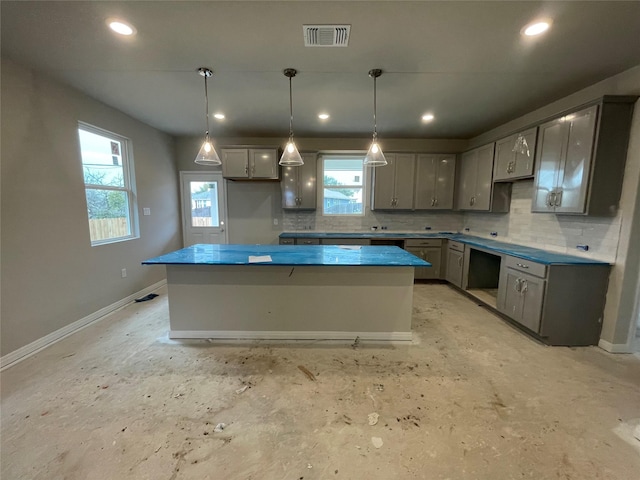 kitchen featuring decorative backsplash, a center island, hanging light fixtures, and gray cabinets