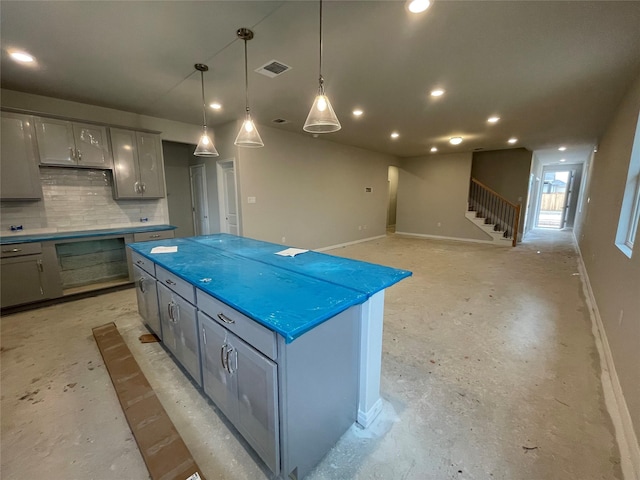 kitchen with gray cabinets, pendant lighting, tasteful backsplash, and a center island