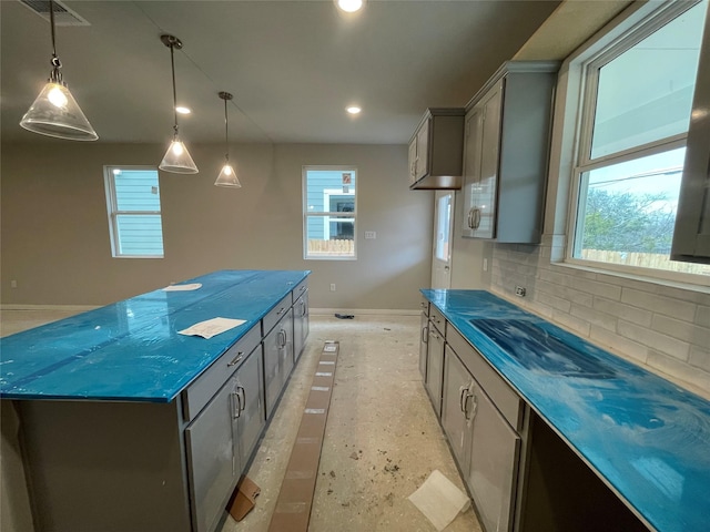 kitchen with tasteful backsplash, gray cabinets, a kitchen island, hanging light fixtures, and dark stone counters