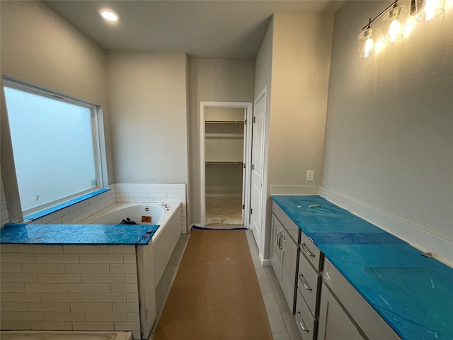 bathroom with a tub to relax in, vanity, and tile patterned floors