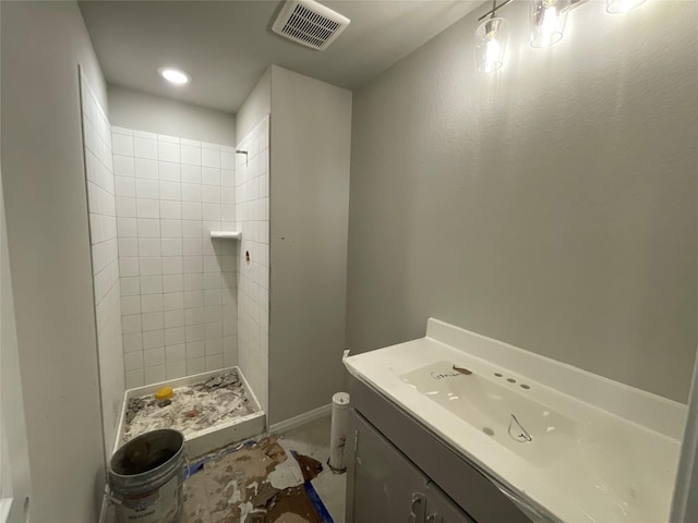 bathroom with tiled shower, vanity, and toilet