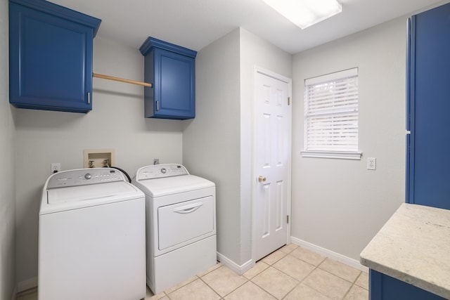 clothes washing area with washing machine and clothes dryer, light tile patterned flooring, and cabinets