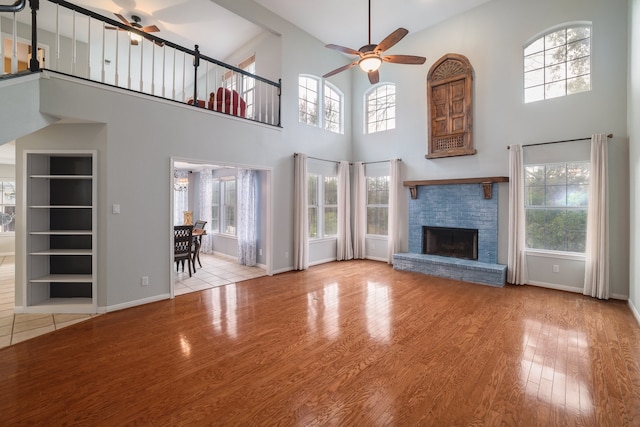 unfurnished living room featuring a brick fireplace, ceiling fan, and plenty of natural light