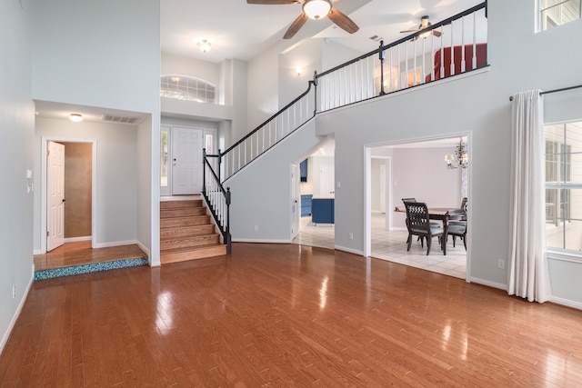 entrance foyer with hardwood / wood-style floors, ceiling fan with notable chandelier, and a towering ceiling