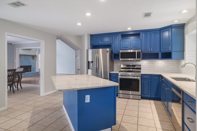 kitchen with blue cabinetry, light stone countertops, sink, a center island, and appliances with stainless steel finishes