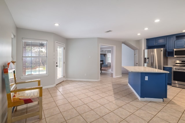 kitchen with light tile patterned flooring, blue cabinets, decorative backsplash, a kitchen island, and stainless steel appliances