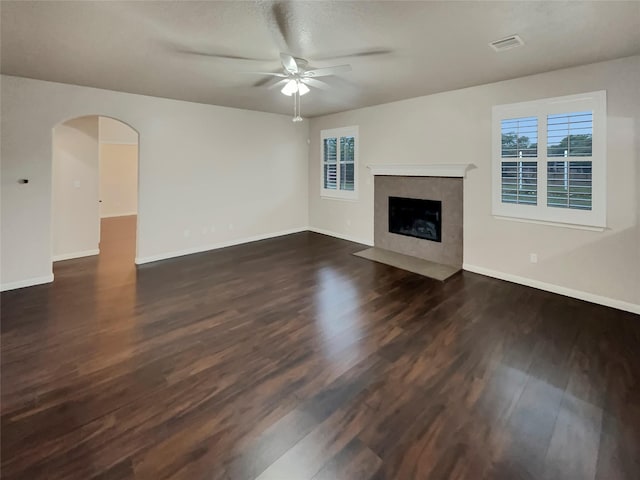 unfurnished living room with a textured ceiling, ceiling fan, dark wood-type flooring, and a high end fireplace