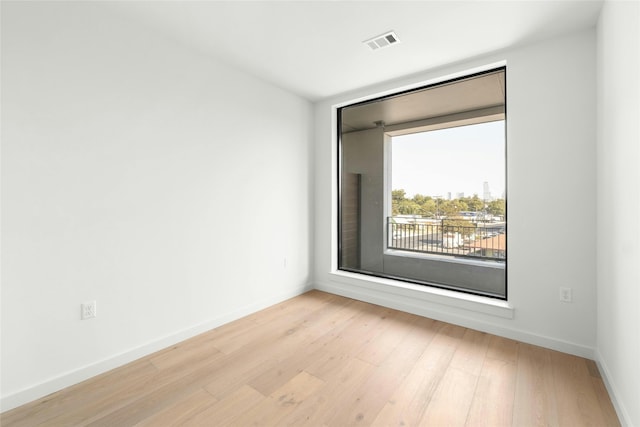 unfurnished room featuring wood finished floors, visible vents, and baseboards