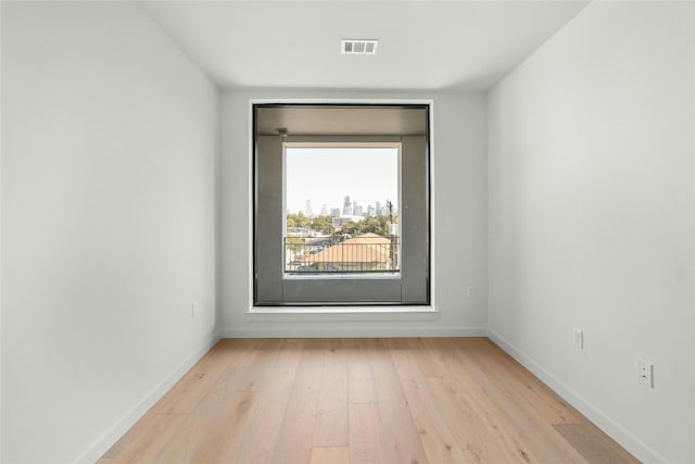 unfurnished room featuring light wood-style floors, visible vents, and baseboards