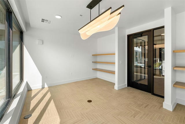 empty room featuring a wealth of natural light, visible vents, and baseboards