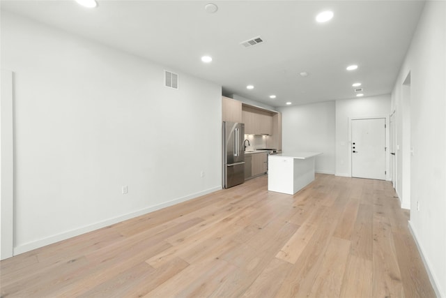 unfurnished living room with recessed lighting, visible vents, light wood-style flooring, and a sink