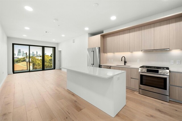 kitchen featuring range hood, appliances with stainless steel finishes, modern cabinets, and a sink