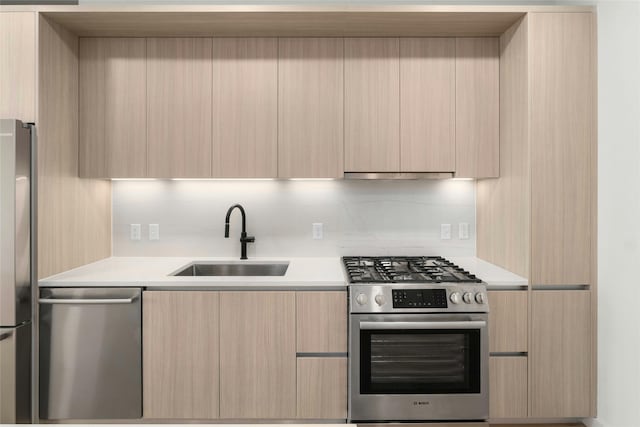 kitchen featuring a sink, modern cabinets, appliances with stainless steel finishes, and light brown cabinetry