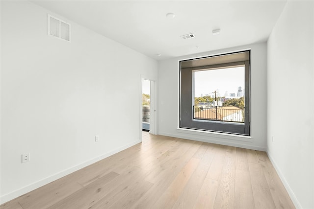 unfurnished room with light wood-style floors, visible vents, and baseboards