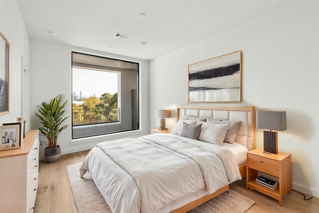 bedroom with light wood finished floors, visible vents, and baseboards