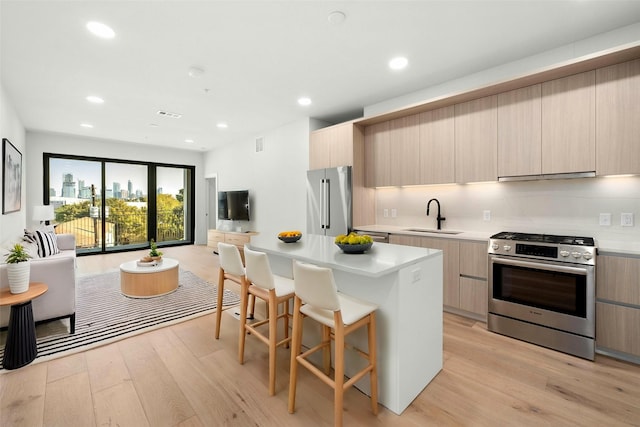 kitchen featuring modern cabinets, appliances with stainless steel finishes, exhaust hood, and a sink