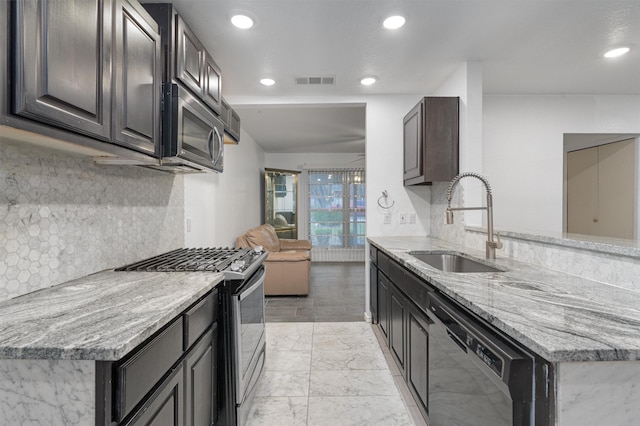 kitchen featuring dark brown cabinetry, light stone countertops, sink, stainless steel appliances, and tasteful backsplash