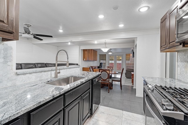 kitchen with light stone countertops, sink, stainless steel appliances, and dark brown cabinets