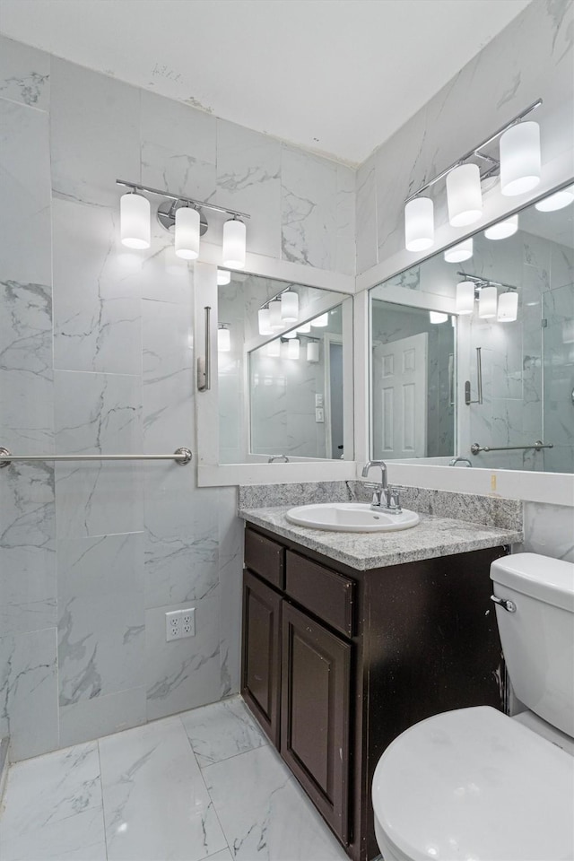 bathroom with vanity, toilet, an enclosed shower, and tile walls