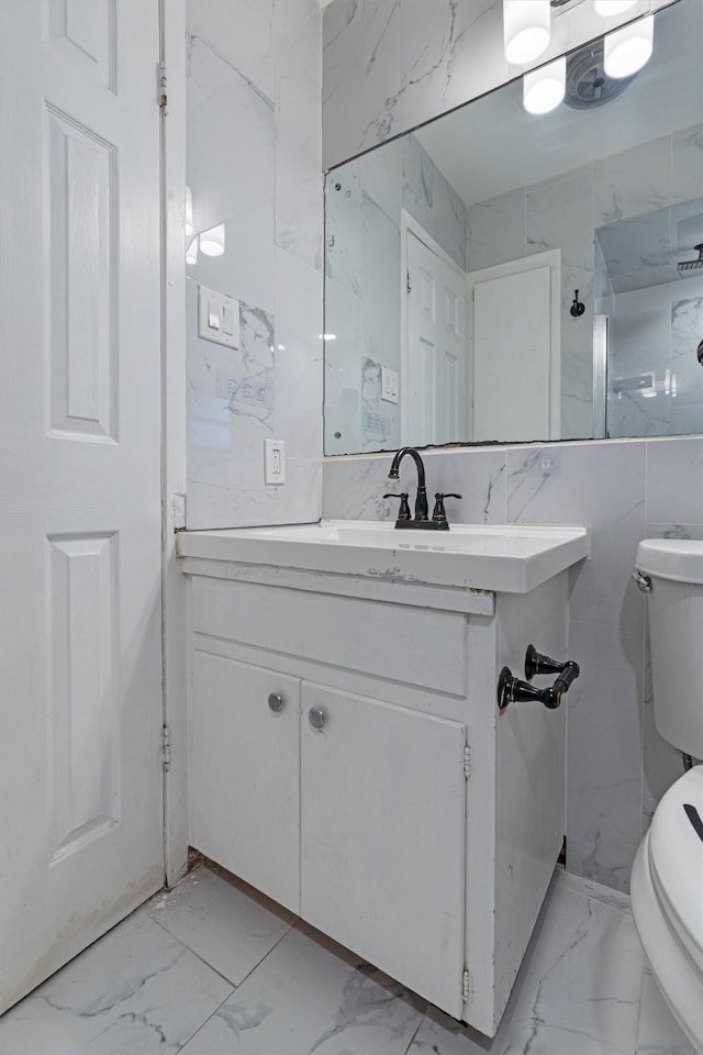 bathroom with vanity, tile walls, and toilet