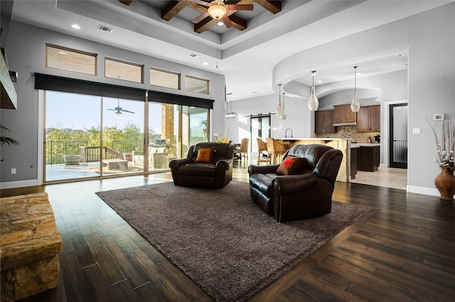 living room featuring beam ceiling, ceiling fan, dark wood-type flooring, coffered ceiling, and a high ceiling