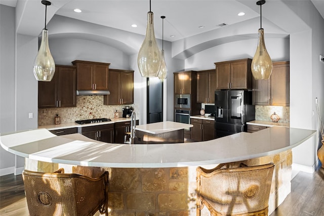 kitchen with tasteful backsplash, a kitchen bar, decorative light fixtures, and appliances with stainless steel finishes