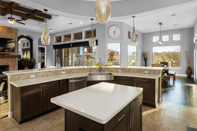 kitchen featuring a spacious island, sink, ceiling fan, a fireplace, and decorative light fixtures