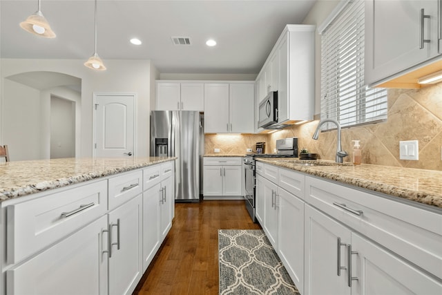 kitchen featuring pendant lighting, backsplash, appliances with stainless steel finishes, dark hardwood / wood-style flooring, and white cabinetry