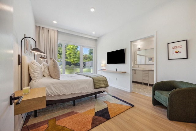 bedroom with sink, connected bathroom, and light hardwood / wood-style flooring