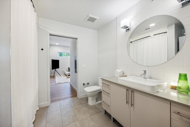 bathroom with tile patterned flooring, vanity, tasteful backsplash, and toilet